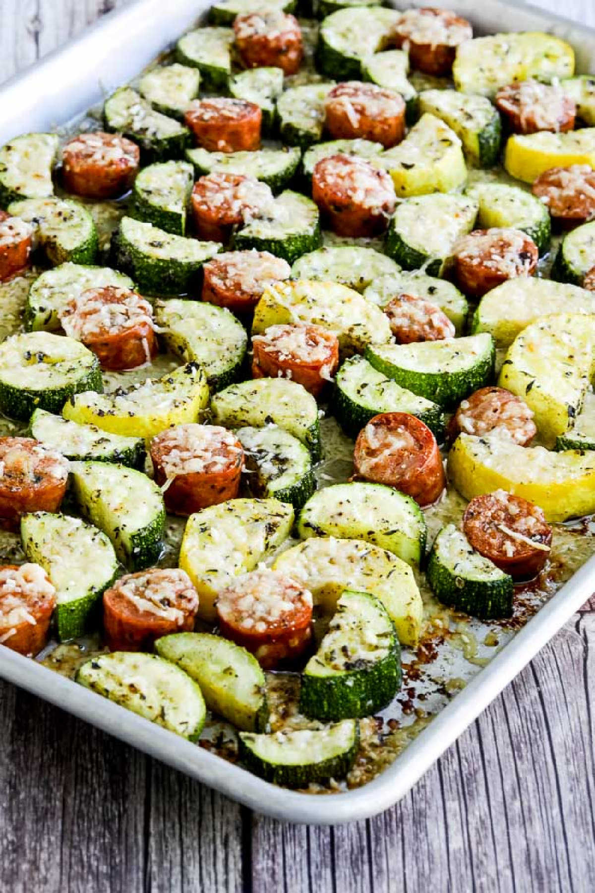 Cheesy Zucchini and Sausage Sheet Pan Meal shown on sheet pan on cutting. board