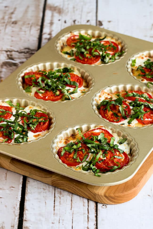 Crustless Tomato Basil Tarts shown in baking pan on cutting board.