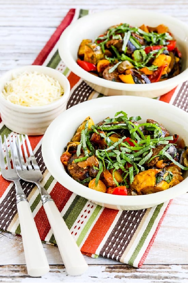 Ratatouille Stew with Italian Sausage shown in serving bowls with parmesan and basil chiffonade