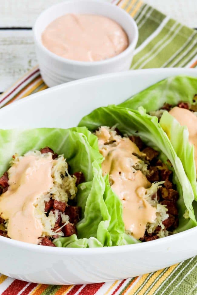 Reuben Sandwich Cabbage Cups shown in serving dish with extra Thousand Island Dressing in back.