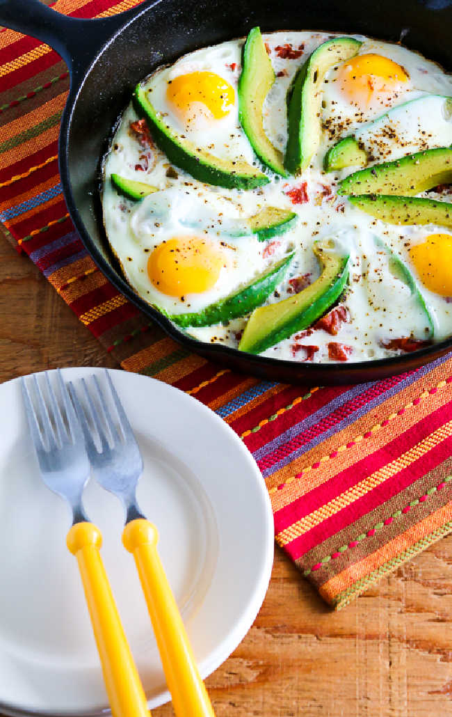 Baked Eggs Skillet with Avocado and Spicy Tomatoes shown in cast-iron skillet