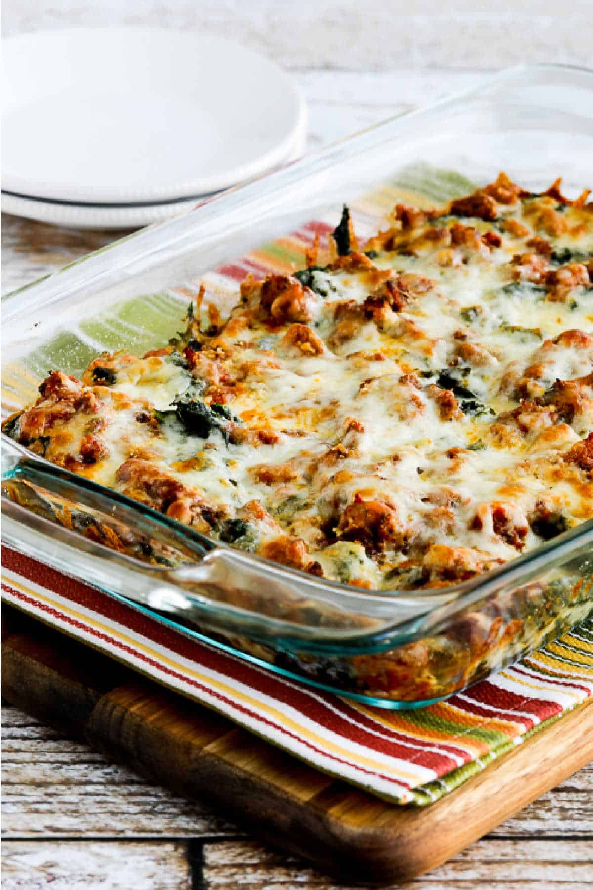 Sausage and Kale Mock Lasagna Casserole shown in baking dish on napkin over cutting board second image