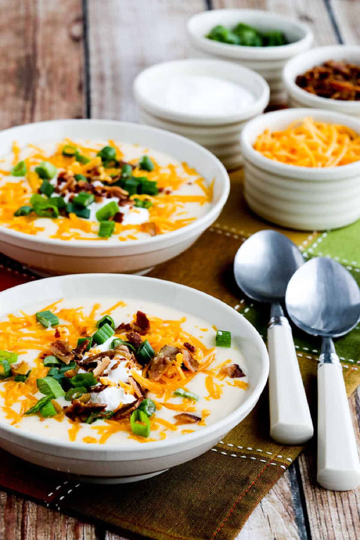 Instant Pot Loaded Cauliflower Soup in two soup bowls with toppings in background