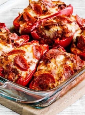 Square image of Sausage and Pepperoni Pizza-Stuffed Peppers shown in baking dish.