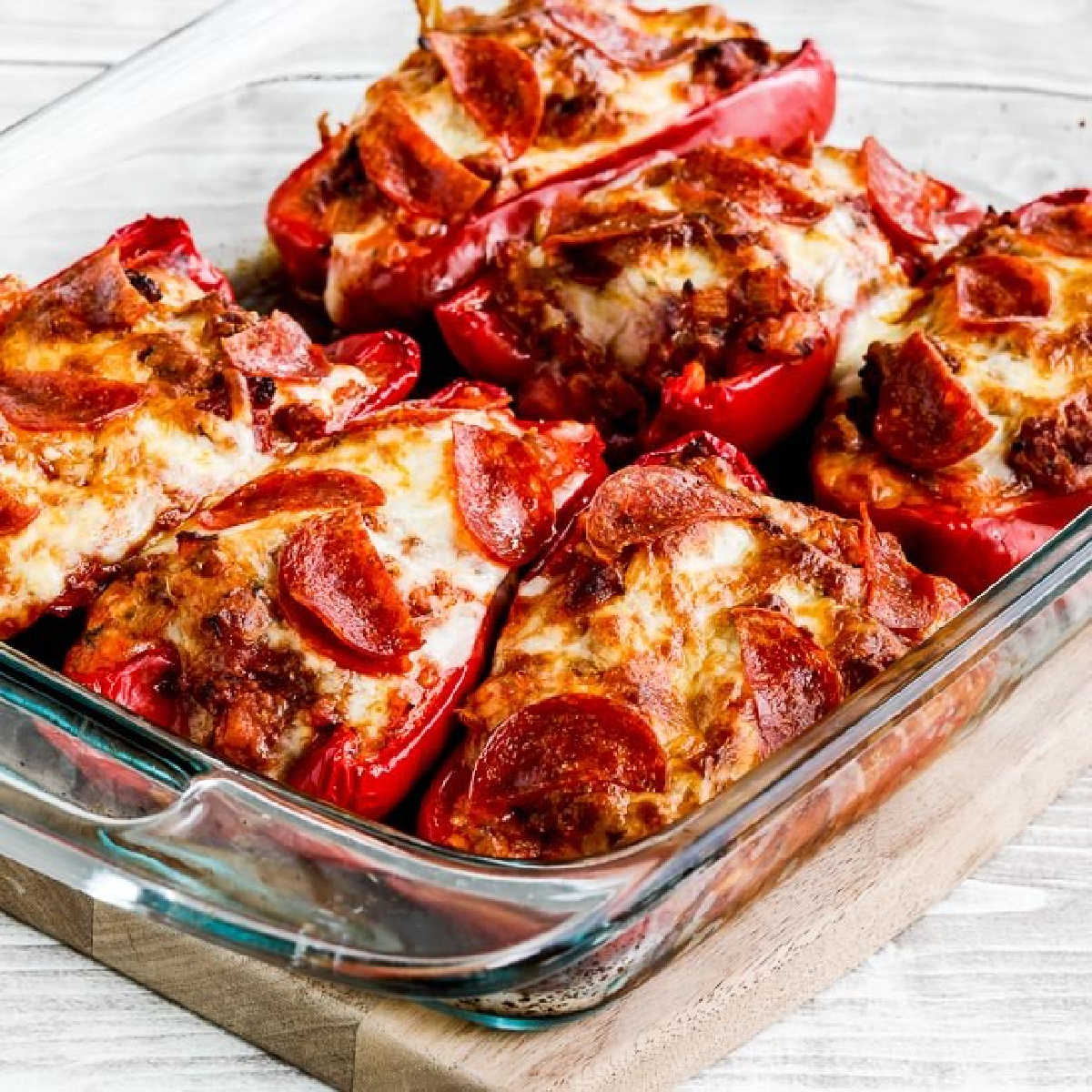 Square image of Sausage and Pepperoni Pizza-Stuffed Peppers shown in baking dish.