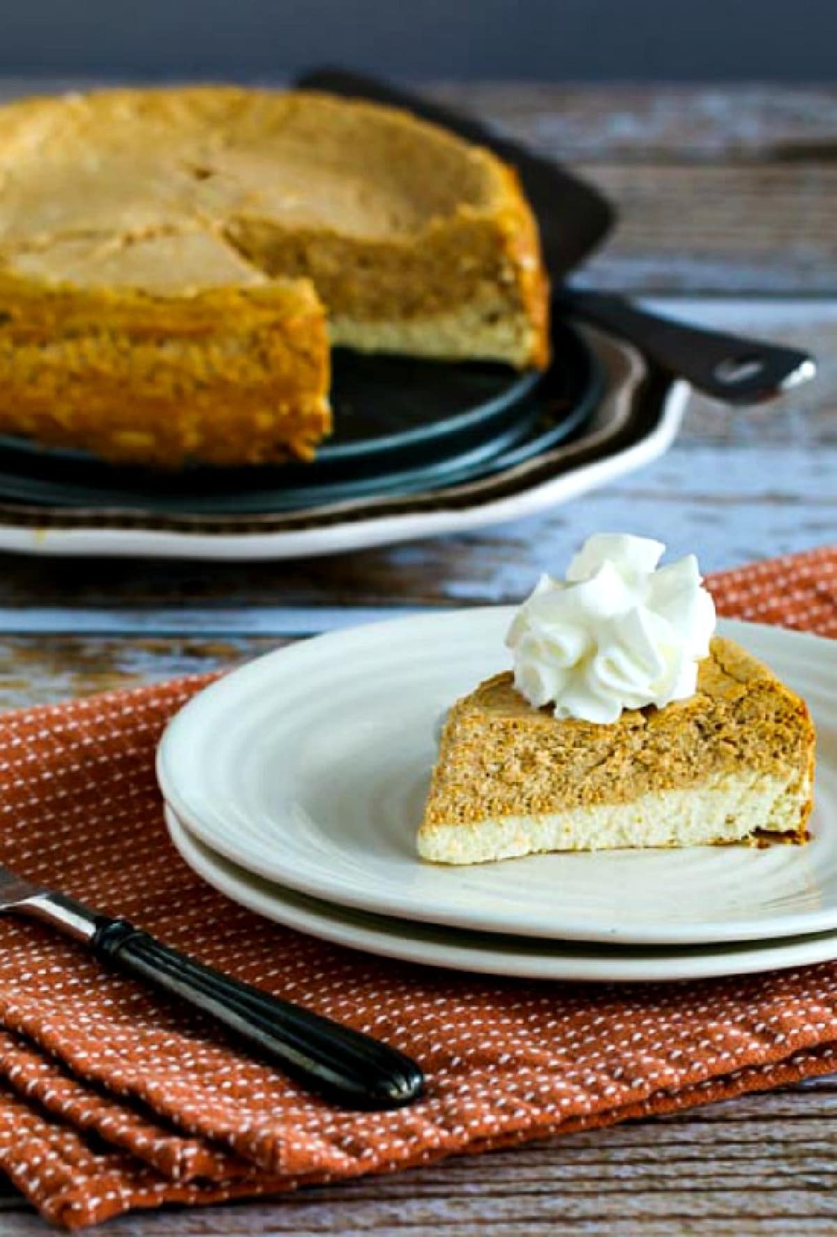 Sugar-Free Layered Pumpkin Cheesecake with one slice on small plate and cheesecake on plate in background