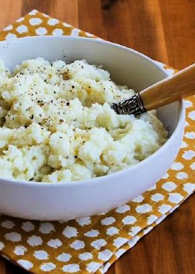 Pureed Cauliflower with Garlic, Parmesan, and Goat Cheese shown in serving bowl with spoon.