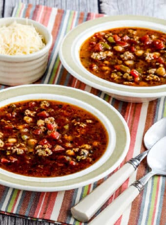 Instant Pot Sausage Soup with Pesto in two bowls with spoons and Parmesan