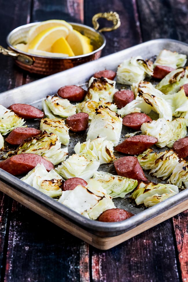 Cabbage and Sausage Sheet Pan Meal shown on sheet pan with lemons in background