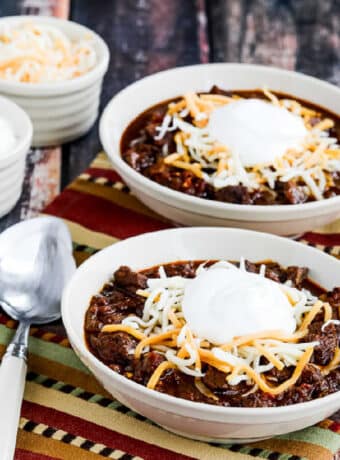 Instant Pot Beef Chili shown in two bowls with cheese and sour cream.