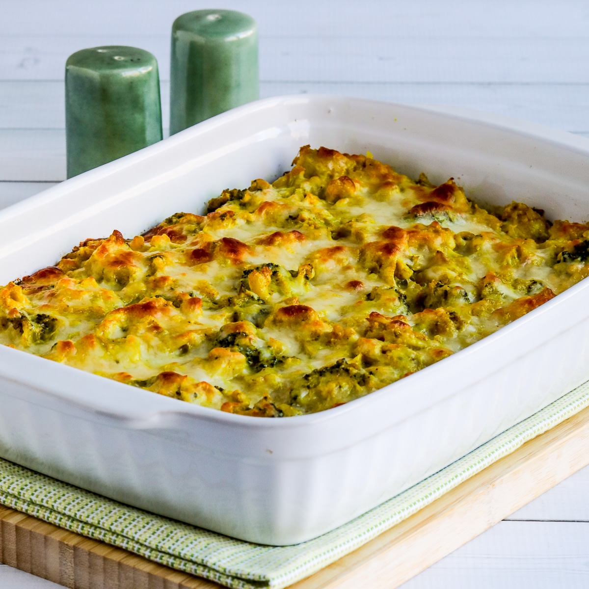 Square image for Chicken Broccoli Curry Casserole with Cauliflower Rice shown in baking pan on napkin and cutting board.