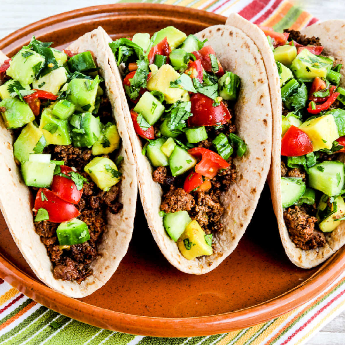 Ground Beef Tacos with Tomato-Avocado Salsa, square image of finished tacos on serving plate