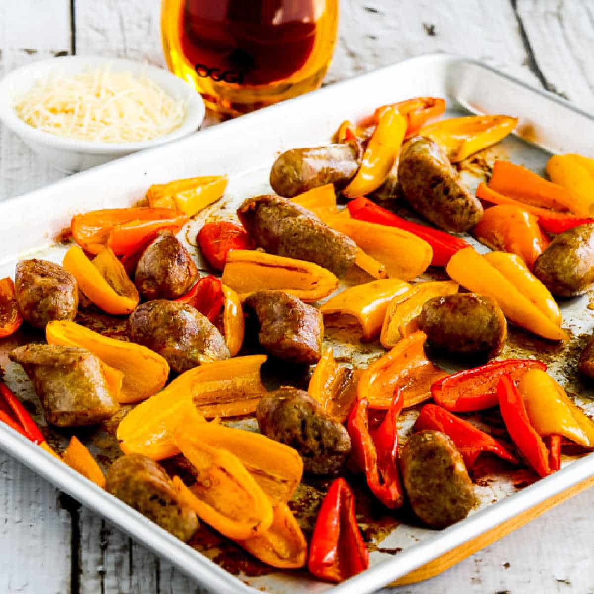 Square image of an Italian sausage and sweet mini pepper sheet pan meal displayed on a sheet pan