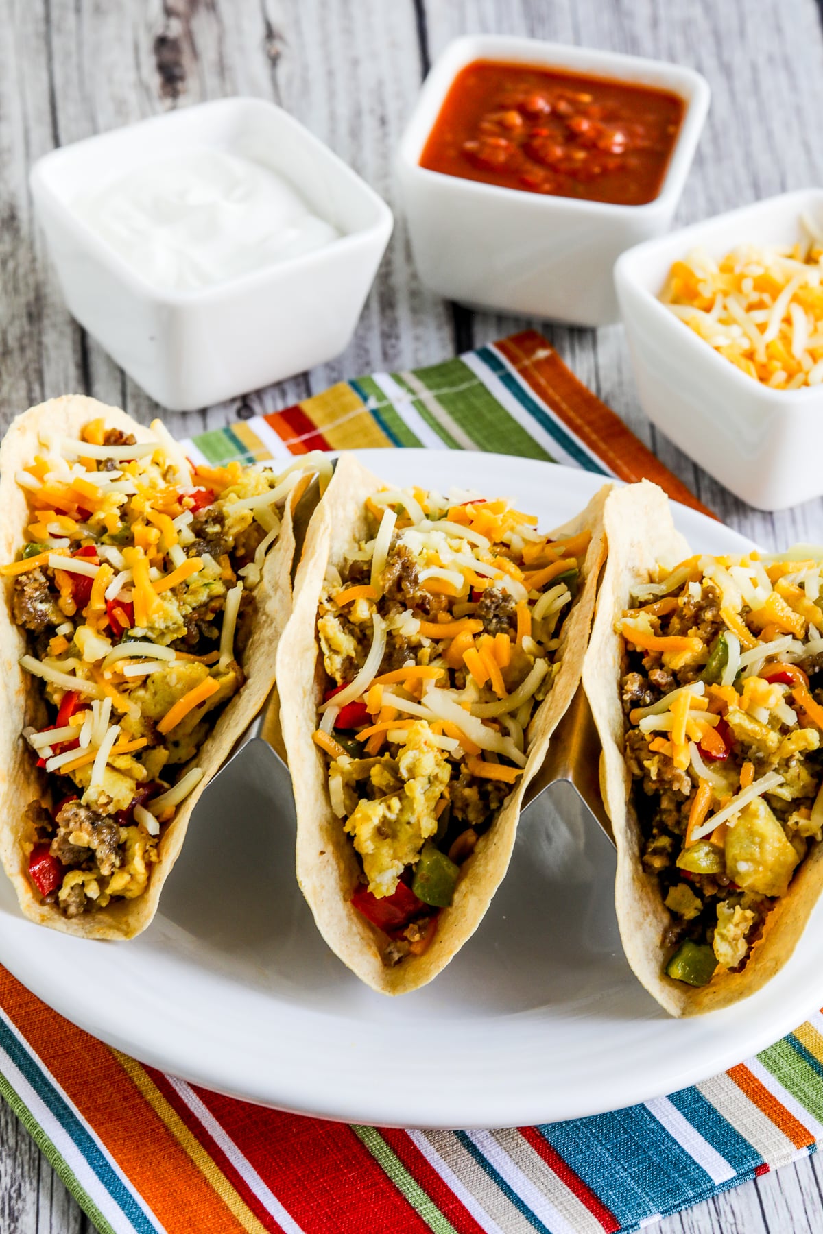 Low-Carb Breakfast Tacos Recipe shown with three tacos in holder on plate.