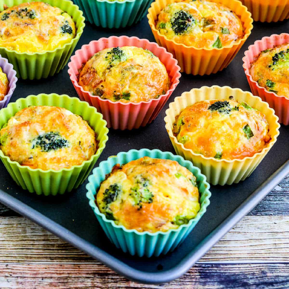 Square image of Keto Egg Muffin Recipe with Broccoli, Bacon, and Cheese shown on baking sheet.