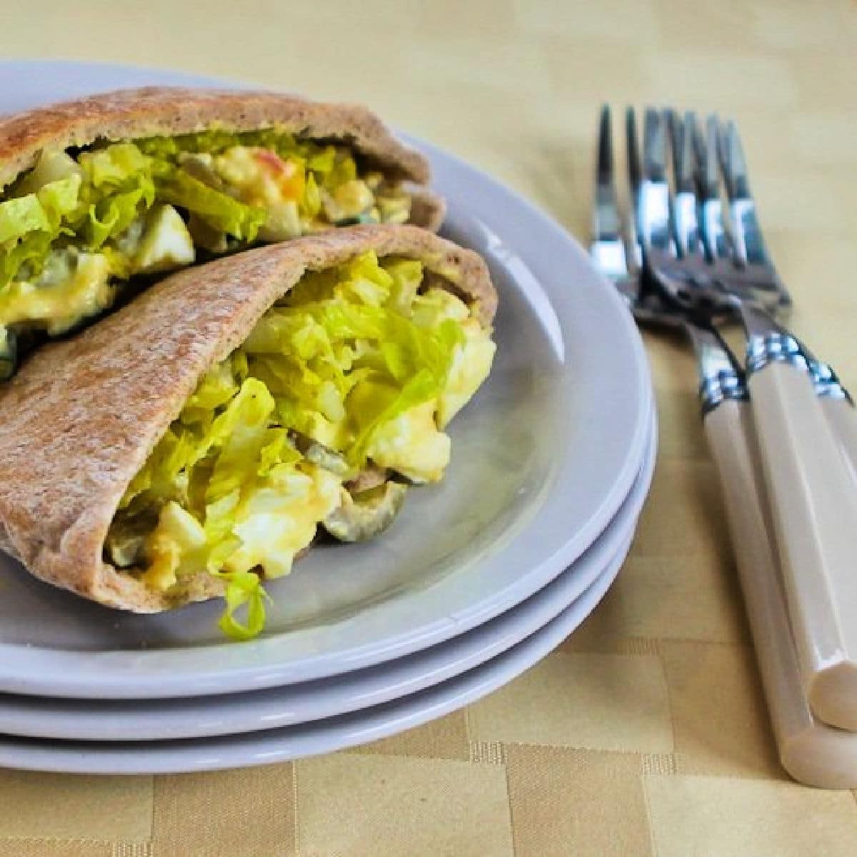 Square image for Egg Salad Pita with Green Olives shown with two pita halves on plate.