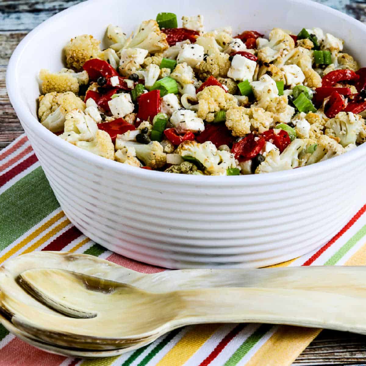 Roasted Cauliflower Salad with Feta, Capers, and Red Pepper shown in serving bowl with large fork.
