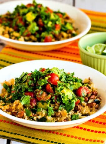 Square image for Cauliflower Rice and Pinto Bean Vegetarian Burrito Bowls shown with two bowls on napkin and bowl of limes on the side.