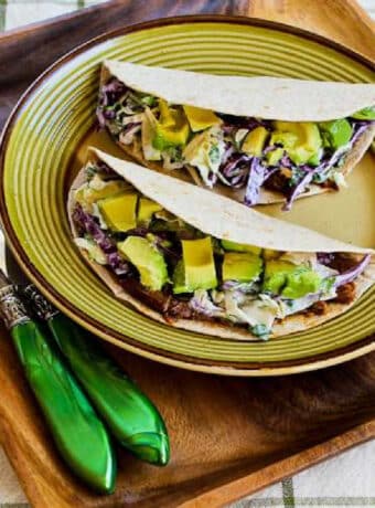 Square image for Shredded Beef Tacos with Spicy Slaw and Avocado shown on serving plate.
