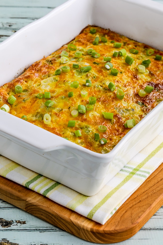 breakfast casserole with green chiles and cheese shown in baking dish on napkin and cutting board