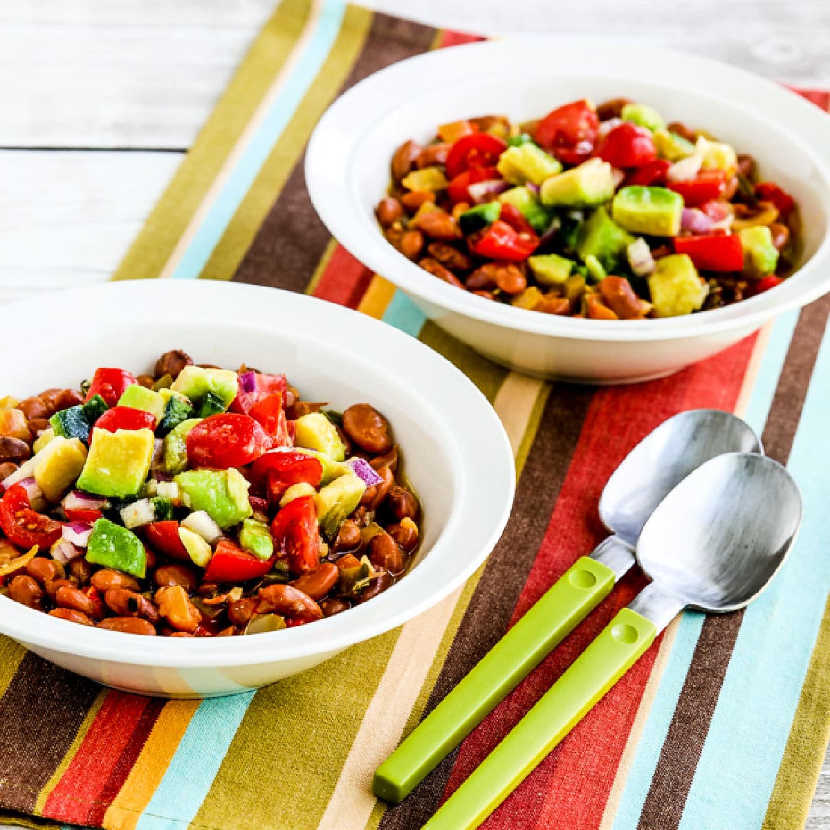 Instant Pot Mexican Beans in two serving bowls on napkin with spoons.