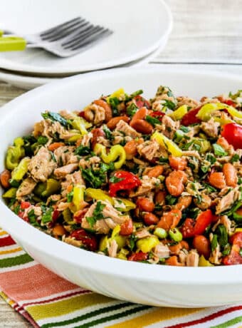 Pinto Bean Salad with Tuna and Peperoncini in serving bowl with plates and forks in back.