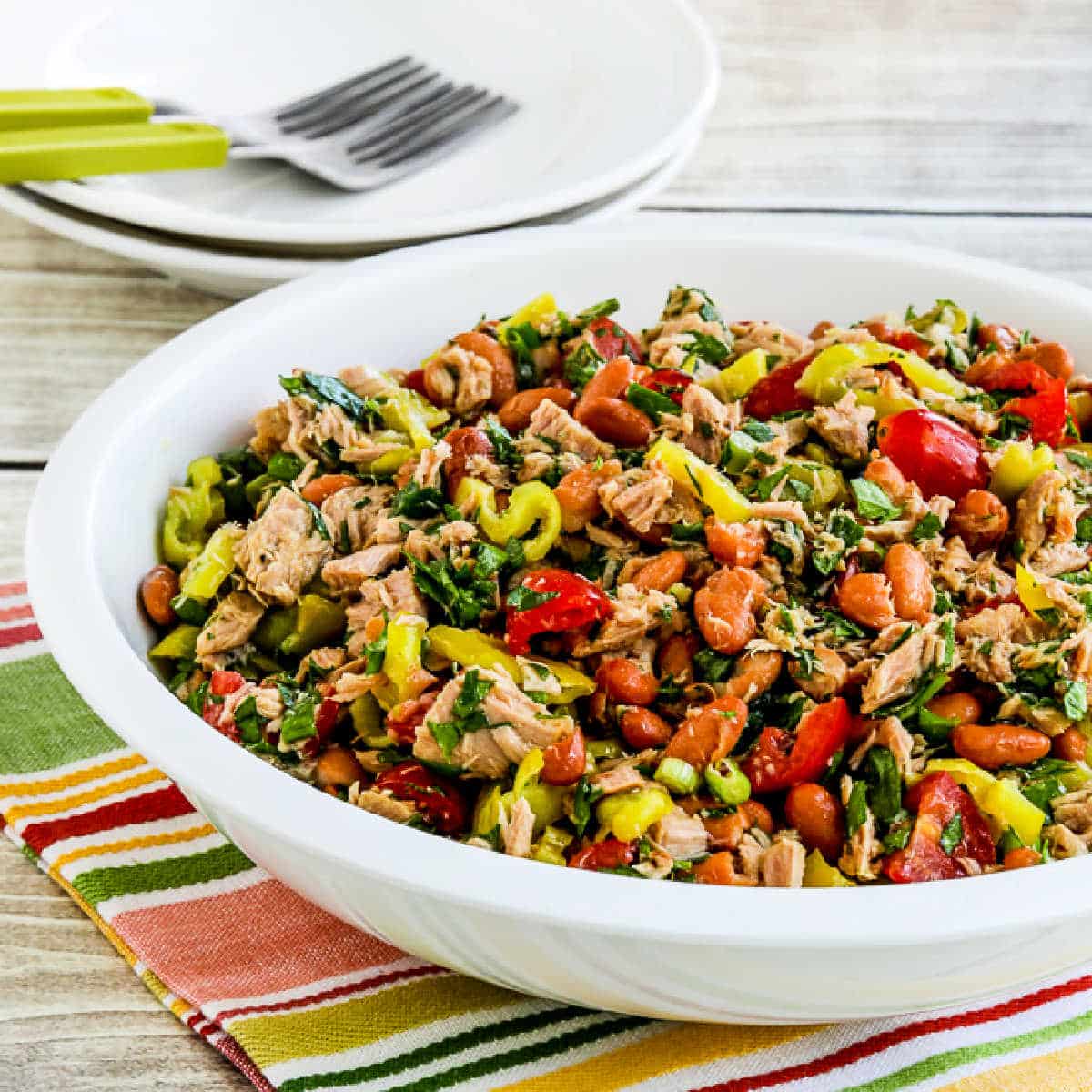 Pinto Bean Salad with Tuna and Peperoncini in serving bowl with plates and forks in back.