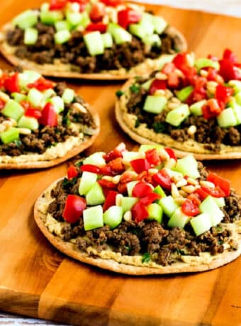 Square image of Middle Eastern Beef Pitas shown on cutting board.