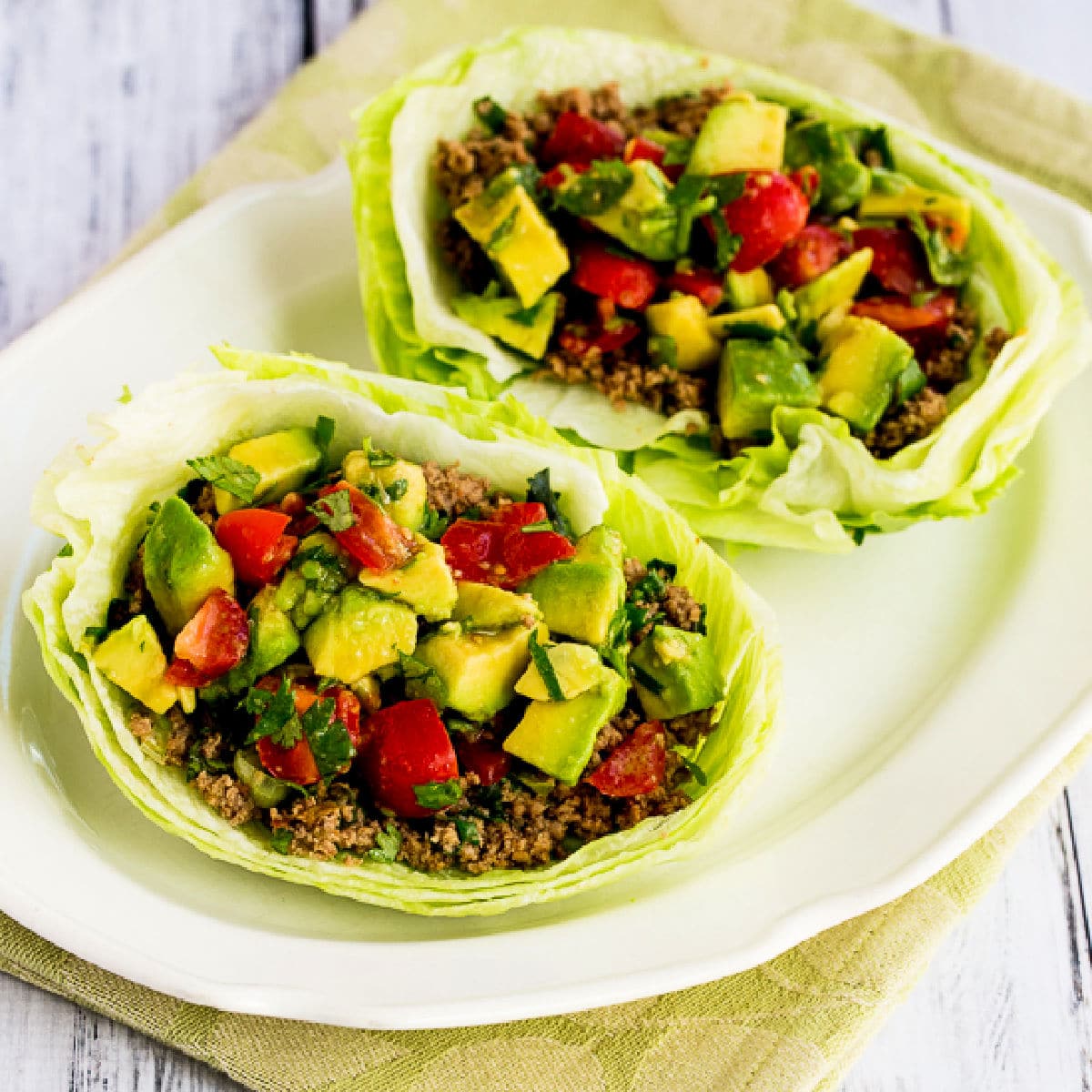 Square image of Turkey Lettuce Wrap Tacos with two taco lettuce wraps on serving plate.