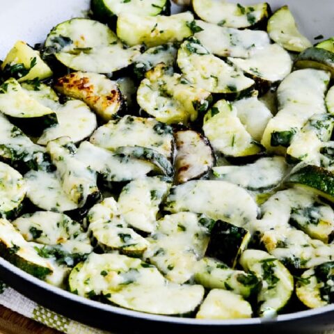 Cheesy Zucchini with Garlic and Parsley shown in pan on cutting board