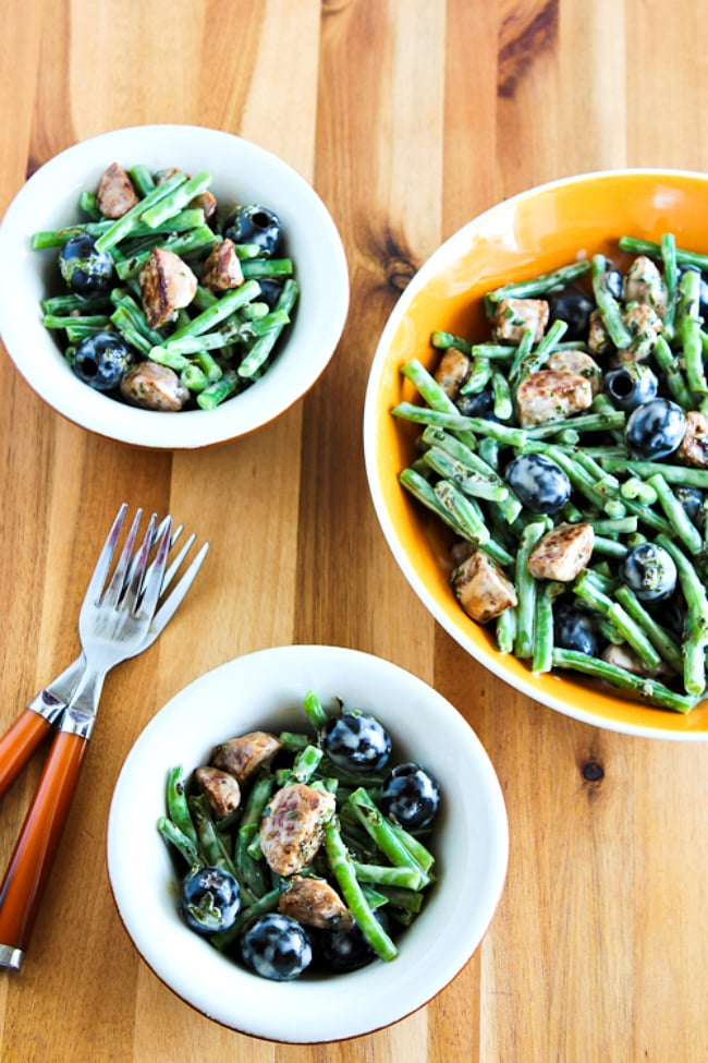 Green Bean Salad with Sausage and Olives shown in serving bowl and two individual servings in smaller bowls