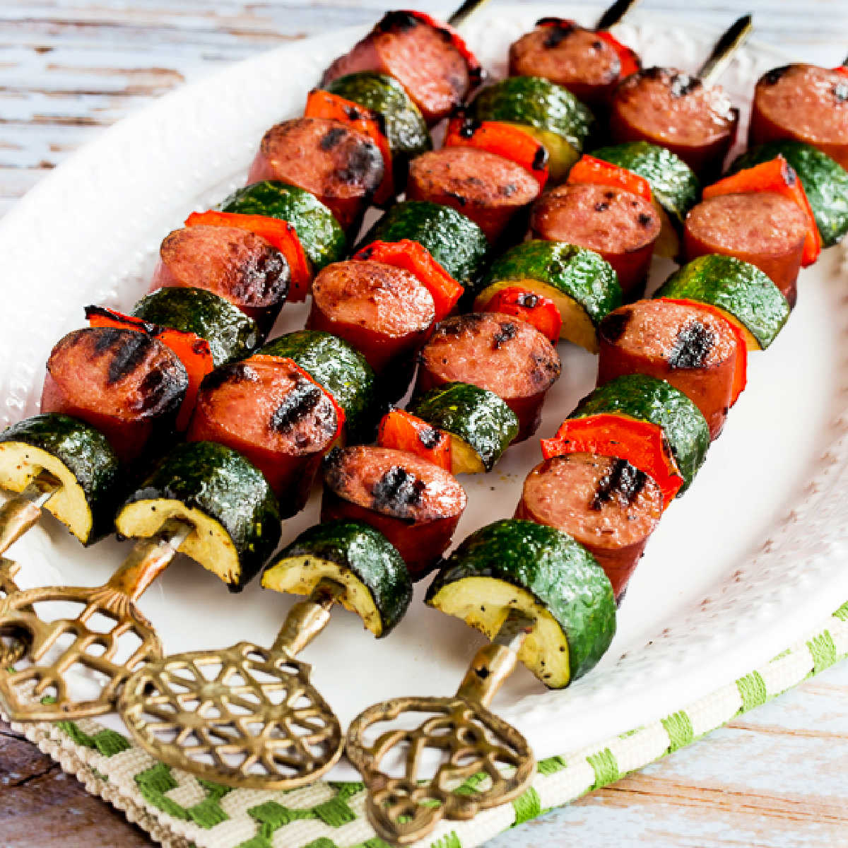 Easy Kabobs with Zucchini and Sausage shown on skewers on serving plate.