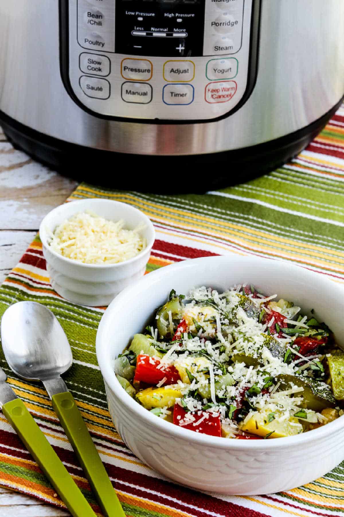 Instant Pot Ratatouille in serving dish with spoons, Parmesan, and Instant Pot in background