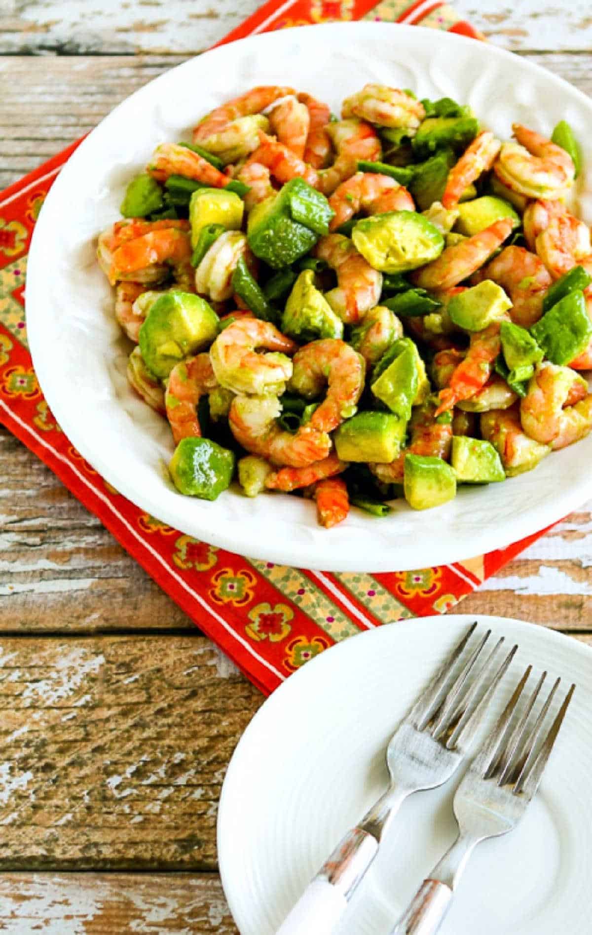 Shrimp and Avocado Salad on serving bowl with plates and forks beside it