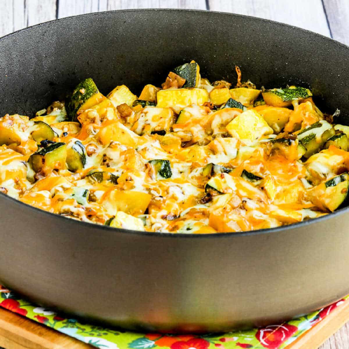 Cheesy Calabacitas shown in frying pan with melted cheese on top.