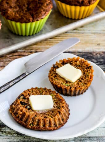 Flourless Keto Zucchini Muffins with one muffin on plate, cut in half, with pats of butter.