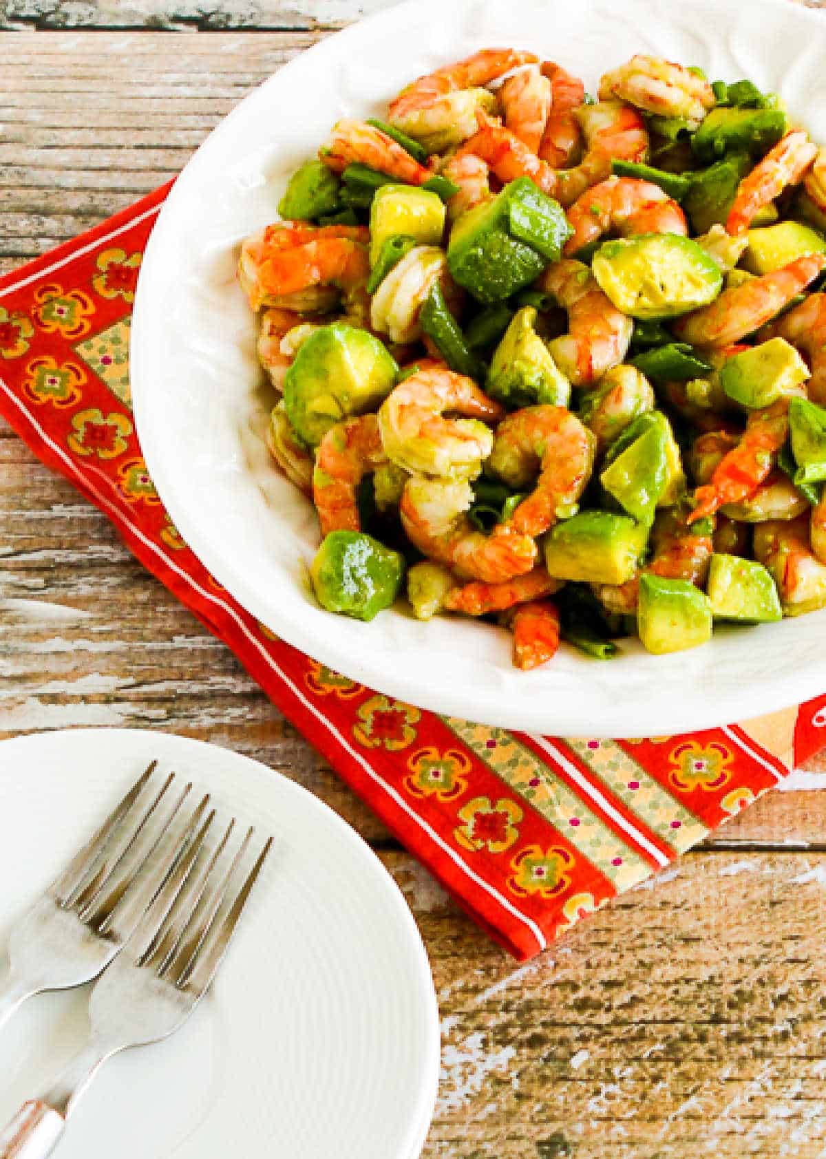 Shrimp and Avocado Salad in serving bowl on napkin with plates-forks