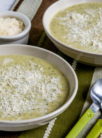 Square image for Zucchini and Yellow Squash Soup in two bowls with spoons and Parmesan.