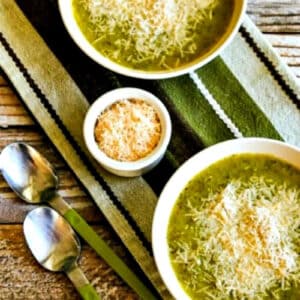 square image with two bowls of zucchini soup loaded with Parmesan