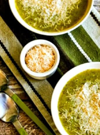 square image with two bowls of zucchini soup loaded with Parmesan