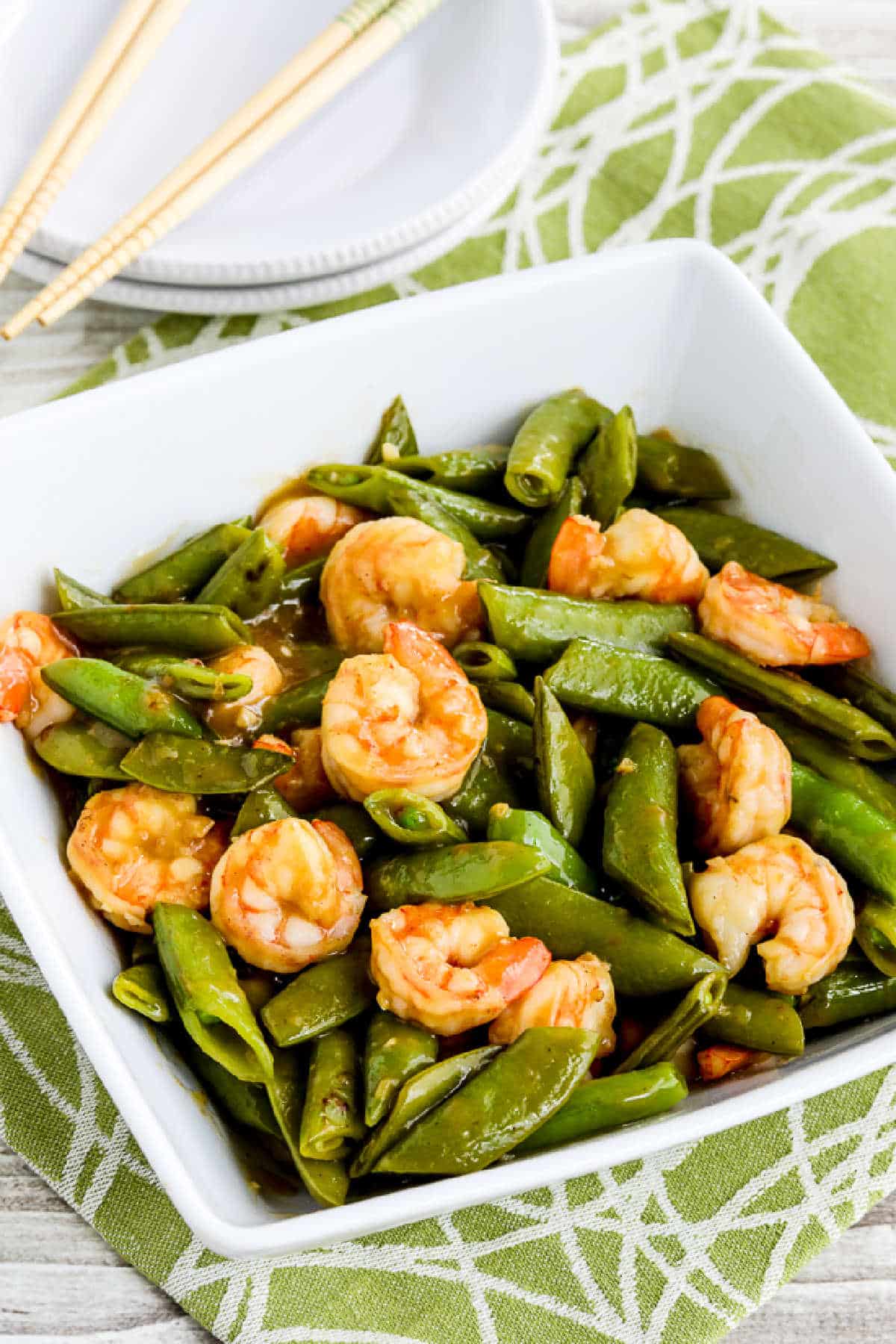 Stir-Fried Shrimp and Sugar Snap Peas in bowl with plates and chopsticks