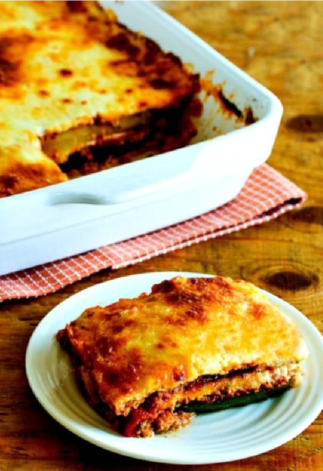 Grilled Zucchini Lasagna shown in baking dish with one piece on serving plate in front.