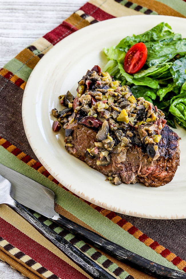 Pan-Grilled Steak with Olive Sauce shown on serving plate with salad