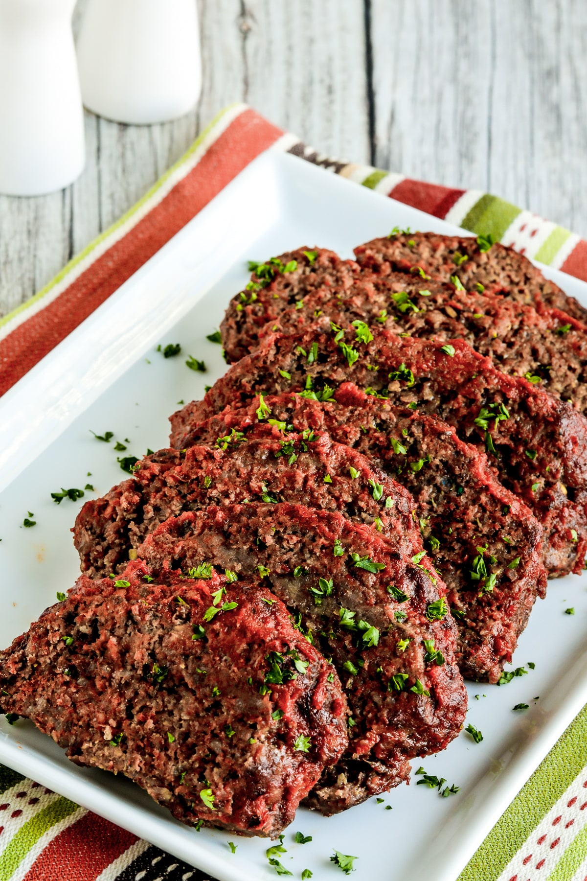 Beef and Sausage Italian Meatloaf shown on serving plate, sprinkled with parsley.