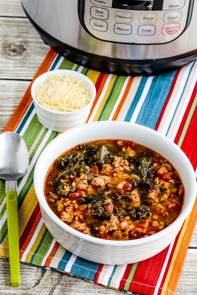 Instant Pot Sausage and Kale Soup photo of finished soup in bowl with Instant Pot behind it