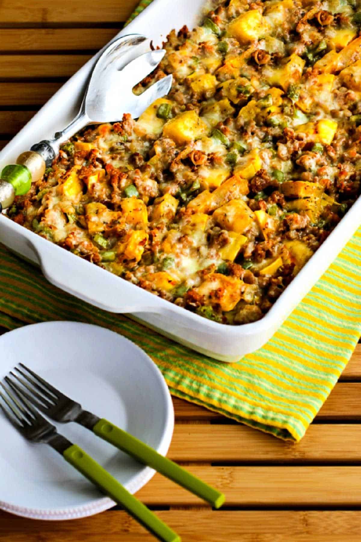 Delicata Squash and Sausage Gratin shown in baking dish with plates, forks, and serving spoon