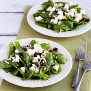 Spinach Salad with Goat Cheese shown on two plates with forks and green napkin