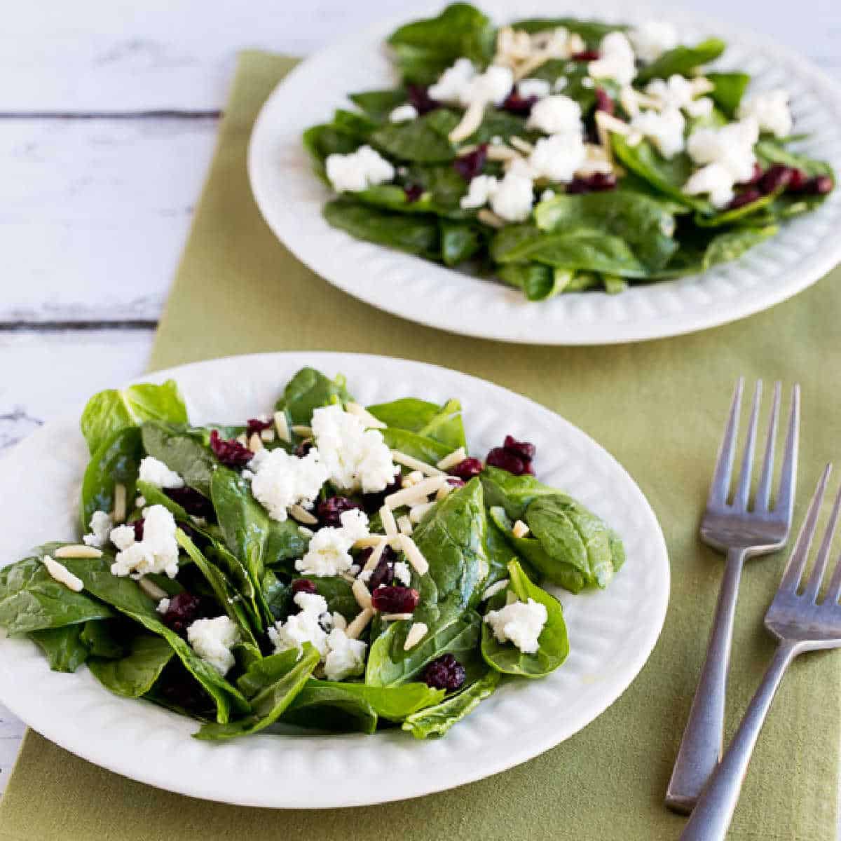 Spinach Salad with Goat Cheese shown on two plates with forks and green napkin