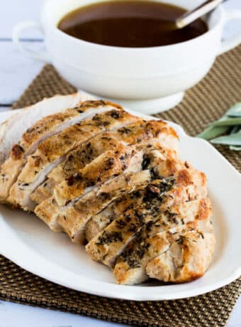 Square image of Slow Cooker Turkey Breast shown on platter with gravy in back.