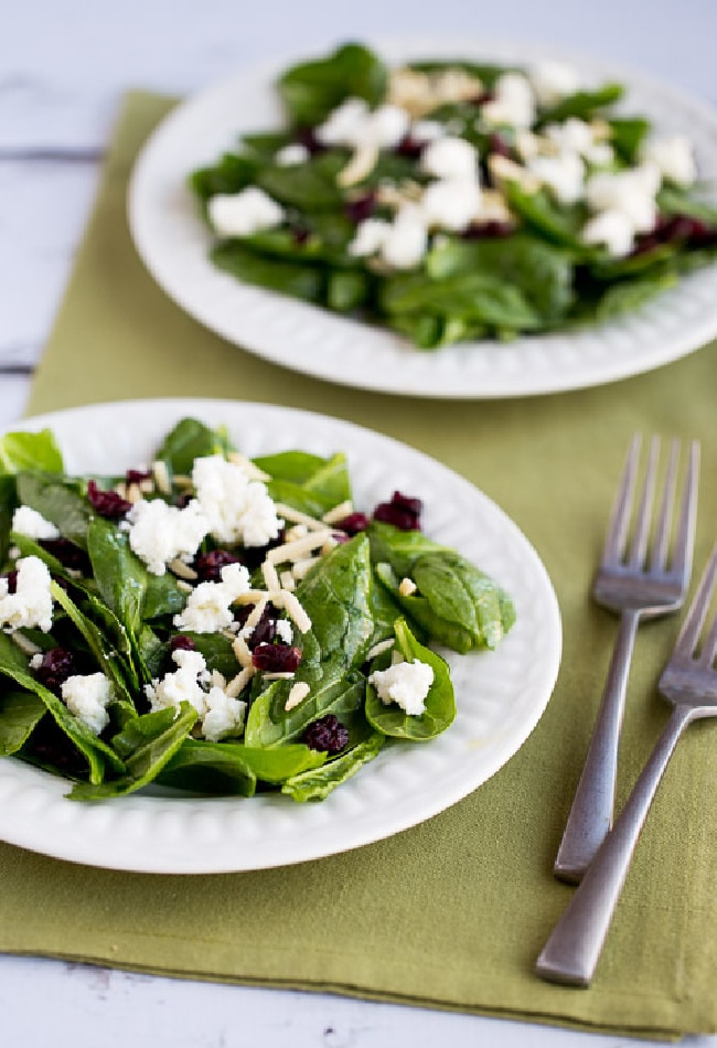 Spinach Salad with Goat Cheese shown on two serving plates with napkin and forks